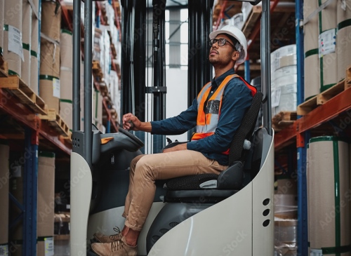 Warehouse worker operating a forklift and staring at shelving