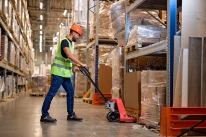 Worker in Warehouse Using Hand Pallet Stacker to Transport Goods